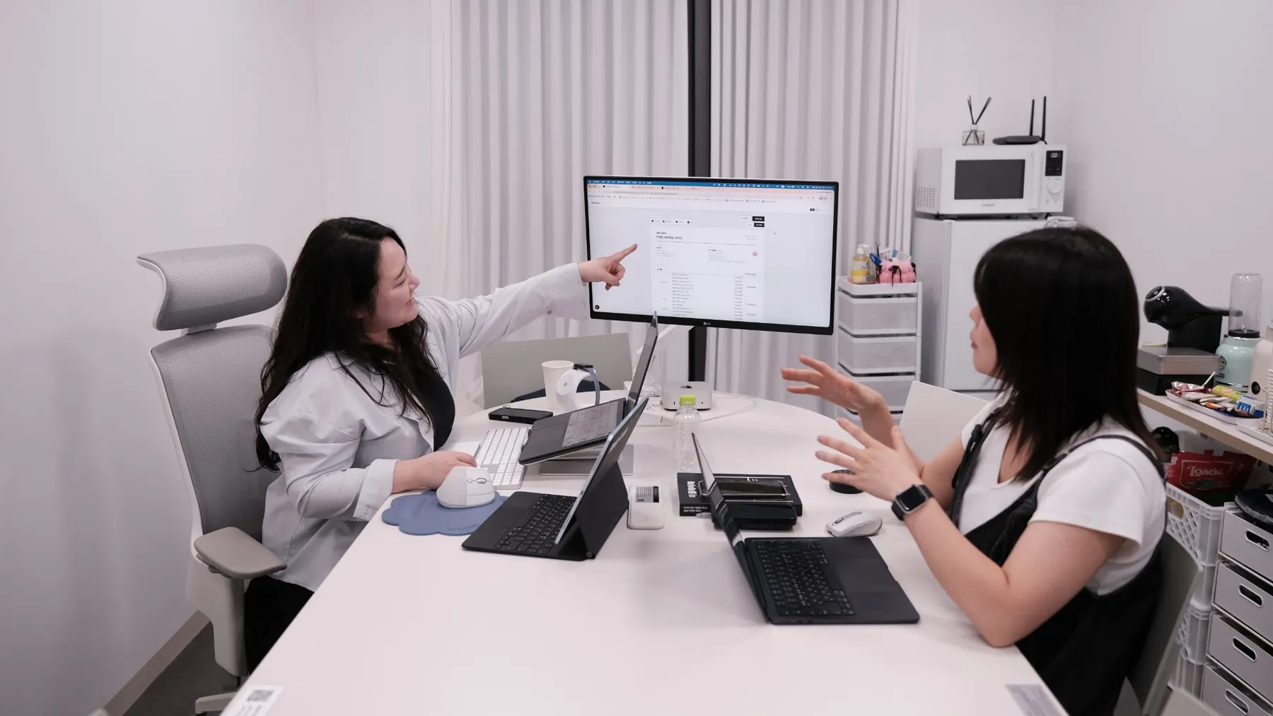 모니터 화면을 가리키며 업무 시스템을 설명하는 모습